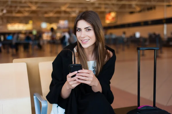 Genç kadın yolcu kapısında terminalde bekleyen akıllı telefon — Stok fotoğraf