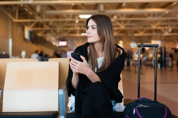 Genç kadın yolcu kapısında terminalde bekleyen akıllı telefon — Stok fotoğraf