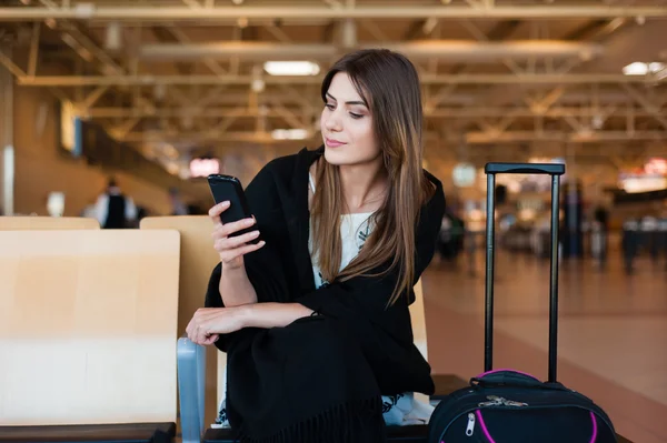 Jeune passager femme sur téléphone intelligent à la porte d'embarquement en attente dans le terminal Images De Stock Libres De Droits