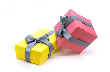 Beyaz arkaplanda izole edilmiş kurdeleli sarı ve kırmızı hediye kutusu