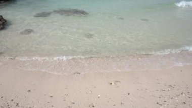 Deniz suyu çok berrak ve beyaz kumsalda el sallıyor..