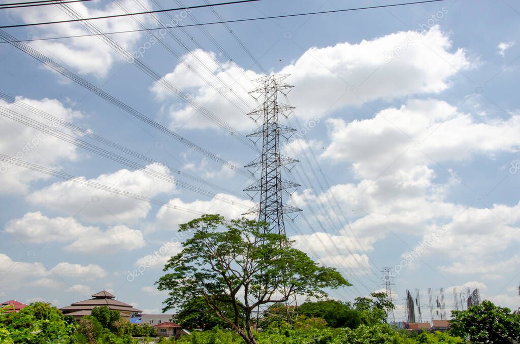Electricity power line tower with tree and village background
