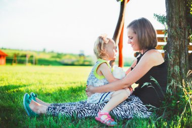 Anne ve küçük kızı çimlere oturup ve söz