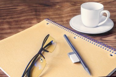 kalem ve defter, kahve, gözlük, silgi, bir tahta üzerinde