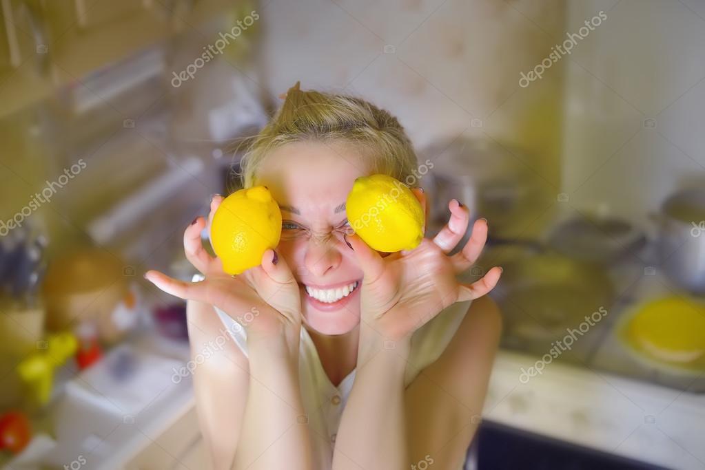 Girl holding lemons in the kitchen around the eyes smiling — Stock