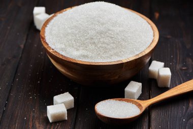 Beyaz kum ve ahşap zemin üzerinde kalın şeker ile kase ve kepçe