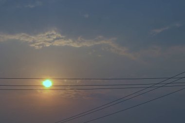 Yüksek voltaj hatları ve altın gökyüzü silueti.