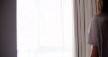 kadın geniş gömlekli pencere yanında duruyor 