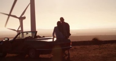 Dışarıda üstü açık bir araba yakınındaki gün batımında kucaklayan Çift