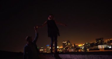 Adam elini çatı kenarında Dengeleme kız arkadaşıyla tutuyor