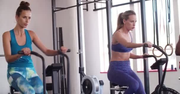 Amigos en ciclismo indoor durante una clase de entrenamiento crossfit — Vídeos de Stock