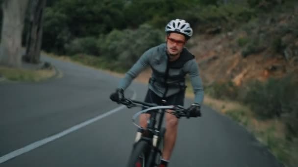 Ciclista montando su bicicleta en un camino de montaña — Vídeos de Stock