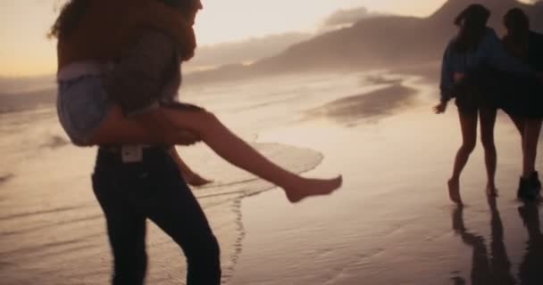 Amigos fazendo passeios de piggyback engraçados na praia — Vídeo de Stock