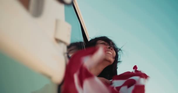 Mujer mirando por la ventana de un coche con bandera — Vídeos de Stock