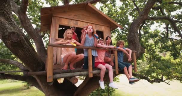 Niños soplando burbujas en el porche de un árbol de madera — Vídeos de Stock