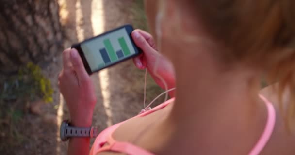 Mujer corredora usando una aplicación de fitness en un teléfono inteligente — Vídeo de stock