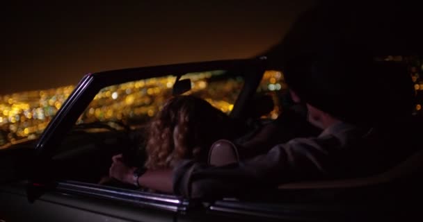 Friends sitting in a convertible car at night — Stockvideo