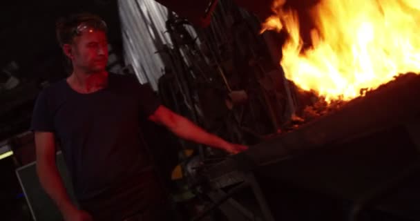 Herrero trabajando plancha en una fragua con fuego — Vídeo de stock