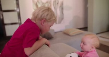 Siblings playing on couch in living room