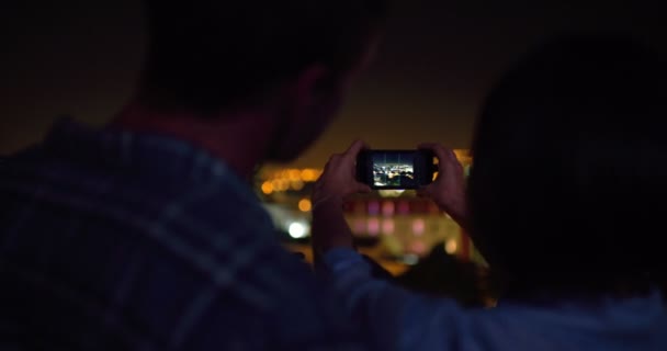 Pareja tomando una foto de la ciudad nocturna con smartphone — Vídeo de stock