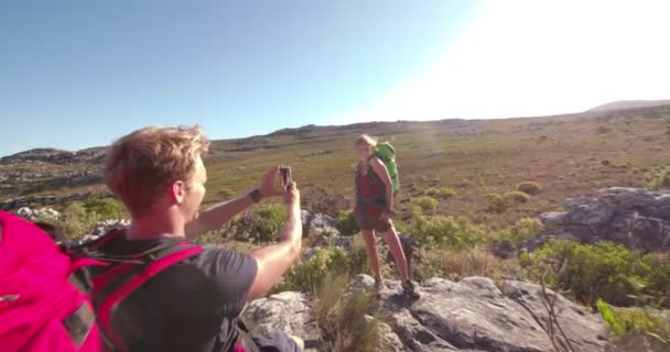 Homem fotografando namorada em caminhadas de férias em montanhas — Vídeo de Stock