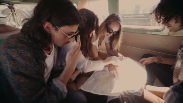 Друзі дивляться на карту в старовинному фургоні — стокове відео