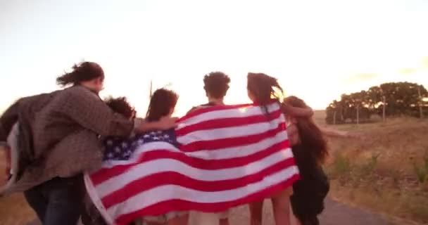 Amigos corriendo por el camino del campo con bandera americana — Vídeo de stock