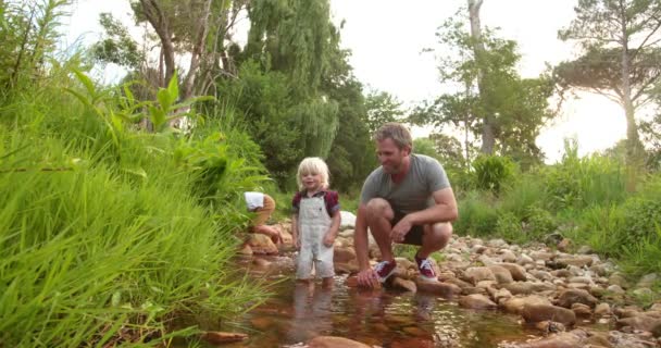 Дитина досліджує світ і річку зі своїм батьком — стокове відео