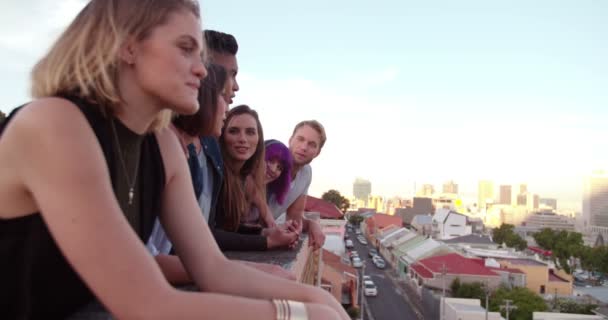 Amigos viendo el atardecer sobre la ciudad desde la azotea — Vídeos de Stock