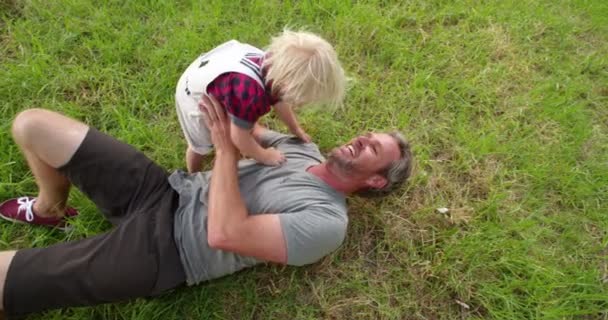 Папа играет со своим маленьким сыном на природе — стоковое видео