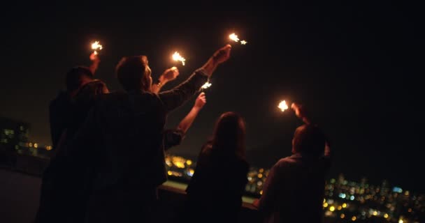 Young friends celebrating on the rooftop with sparklers — Stock Video