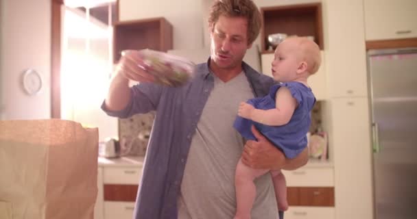 Papa packt mit Säugling Lebensmittel aus — Stockvideo