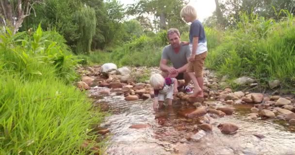 Дети исследуют мир и реку вместе с отцом — стоковое видео