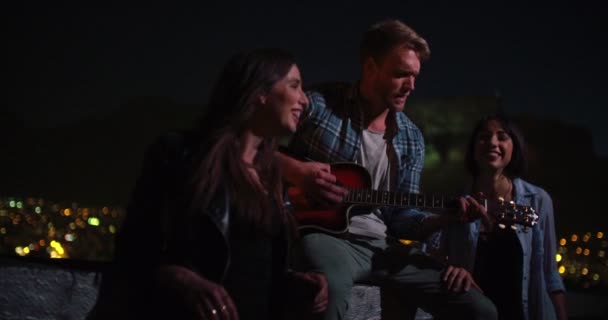 Fiatal férfi játszik gitáron, ő meg a tetőtéri — Stock videók