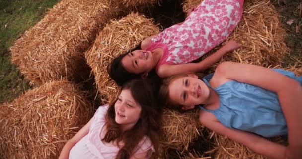 Girls lying on straw in circle with heads together — Stock Video
