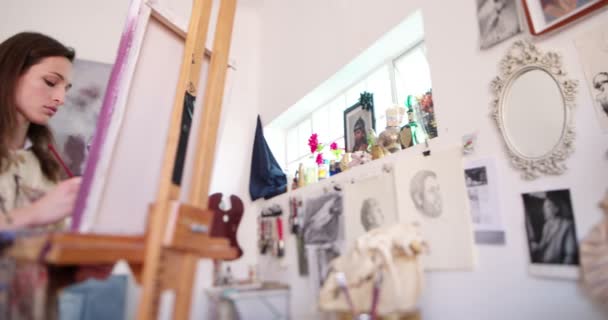 Kunstenaar in haar atelier schilderij een doek op een ezel — Stockvideo