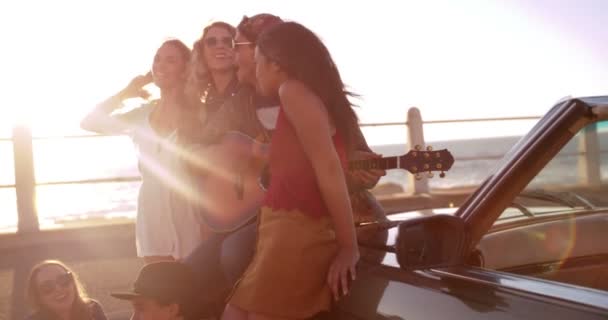 Amigos adolescentes relaxando na praia com uma guitarra — Vídeo de Stock