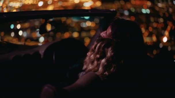 Couple looking at night city lights in a convertible — Stock Video