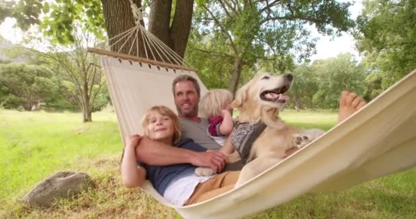 Papa umarmt seine Söhne auf Hängematte draußen — Stockvideo