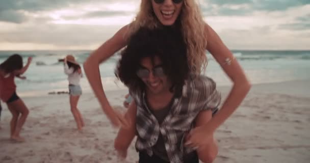 Dziewczyna jeździ Piggyback mężczyzna na plaży — Wideo stockowe
