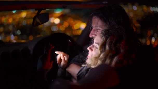 Pareja mirando fotos en un convertible en la noche — Vídeos de Stock