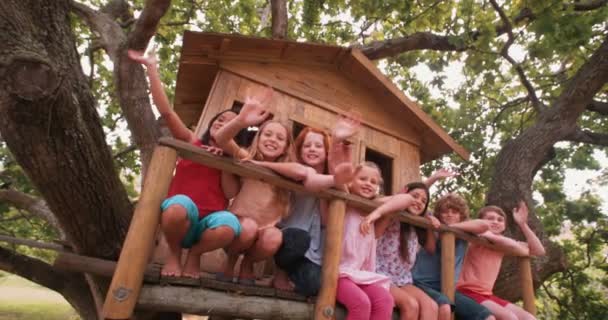 Gruppe von Kindern lächelt und winkt in einem Baumhaus — Stockvideo