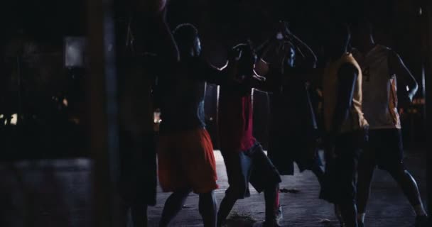 Jugadores de baloncesto jugando en la cancha durante la noche — Vídeo de stock