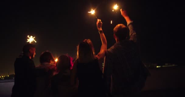 Young friends celebrating on the rooftop with sparklers — Stock Video