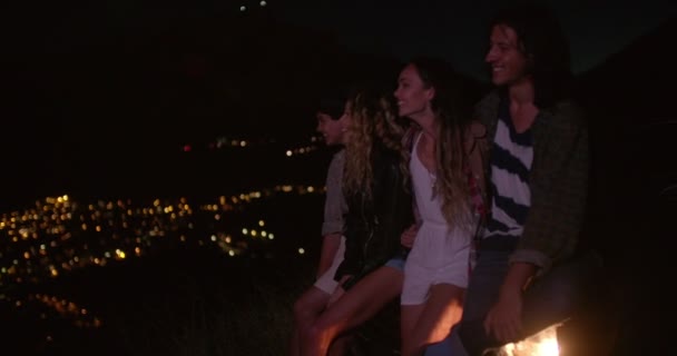 Teens hugging on a convertible looking at night city — Stok video