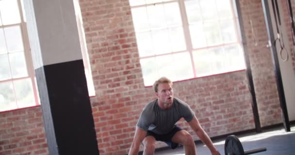 Человек поднимает тяжести во время тренировки по кроссфиту — стоковое видео
