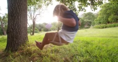 parkta salıncak üzerinde günbatımında oynayan çocuk