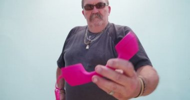Kıdemli adam pembe telefon ile poz