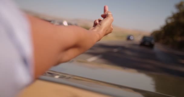 Chica volteando el dedo desde el asiento trasero del coche descapotable — Vídeos de Stock