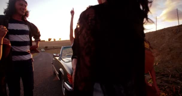 Vänner sitter på en konvertibel huva vid solnedgången — Stockvideo